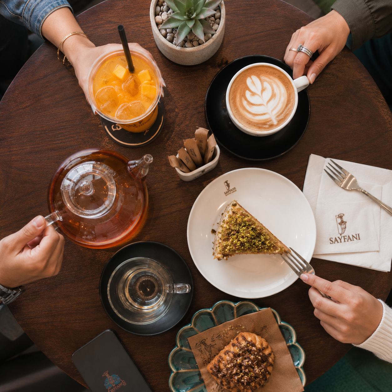 Overhead view of drinks and pastries shared by friends at Sayfani